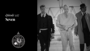Miniature grisée: fond d'écran du film Seven sur laquelle on peut voir le tueur John Doe, menotté et accompagné de deux agents joués par Brad Pitt et Morgan Freeman